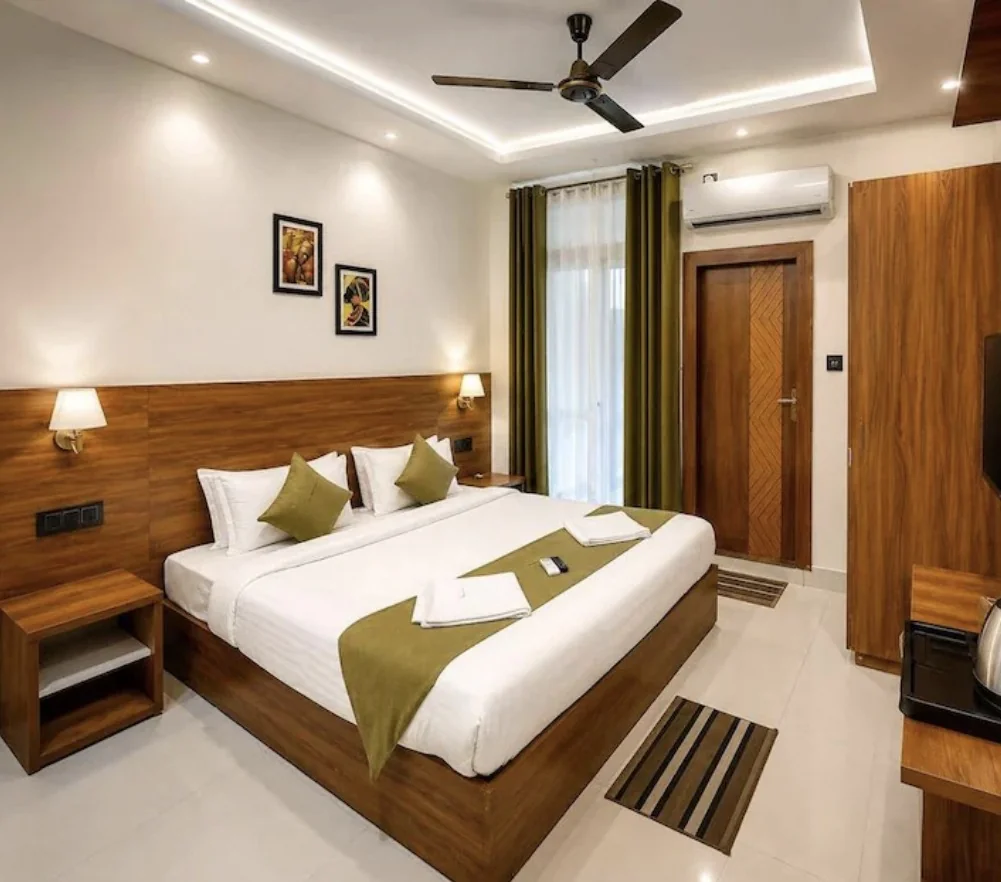Sanskriti guest room with a double bed, wood headboard and sage cushions